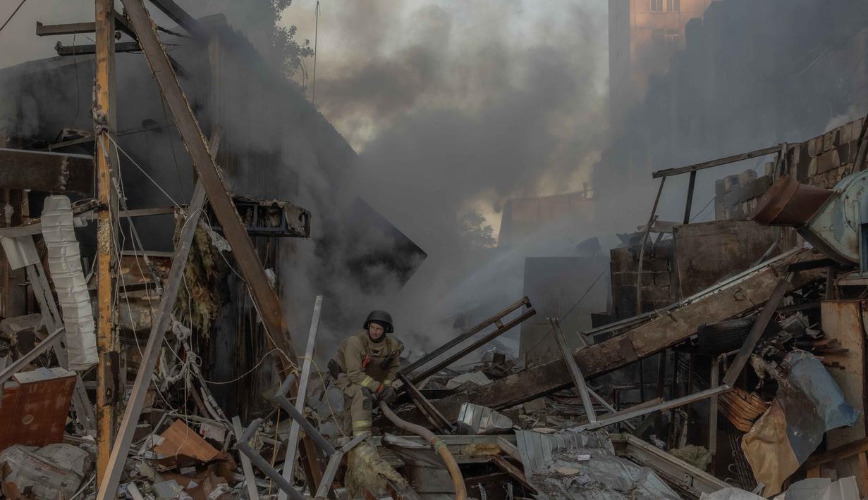 Seorang petugas pemadam kebakaran bekerja di lokasi di samping gedung apartemen bertingkat yang rusak akibat serangan rudal dan pesawat tak berawak besar-besaran Rusia di Kyiv pada Selasa 2 Juni 2026, di tengah invasi Rusia ke Ukraina. (Roman PILIPEY/AFP)