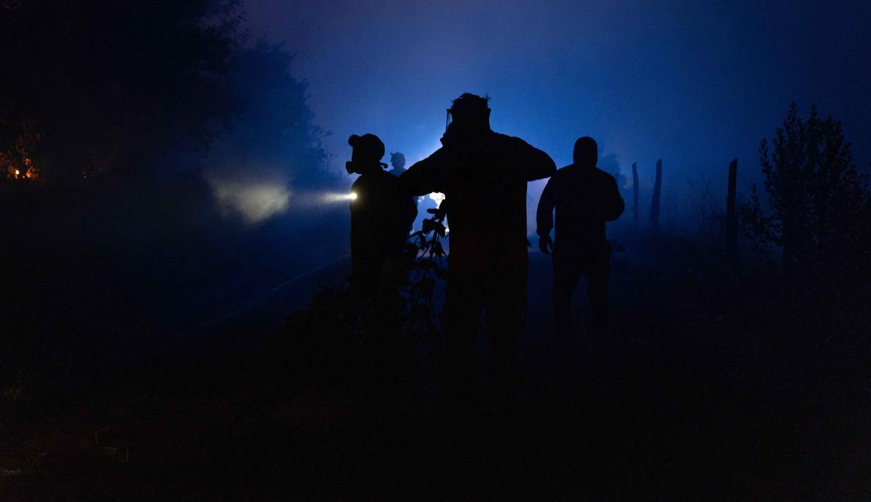 Sebagai informasi, dalam beberapa tahun terakhir, wilayah selatan-tengah Chile kerap dilanda kebakaran hutan besar. Para ahli mengaitkan intensitas kebakaran dengan dampak perubahan iklim, termasuk cuaca ekstrem, kekeringan, hingga banjir. Tampak dalam foto, warga bergotong royong memadamkan vegetasi yang terbakar selama kebakaran hutan di kota Florida dekat kota Concepcion, Chile, pada Senin 19 Januari 2026. (Raul BRAVO/AFP)