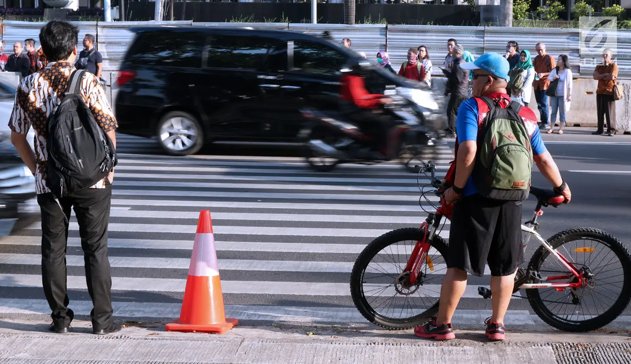 Warga bersiap melintasi Pelican Crossing di sekitar Halte Transjakarta GBK, Jakarta, Jumat, (30/11). Penyeberangan pelican crossing diberlakukan selama revitalisasi jembatan penyeberangan orang (JPO) berlangsung. (Liputan6.com/Helmi Fithriansyah)