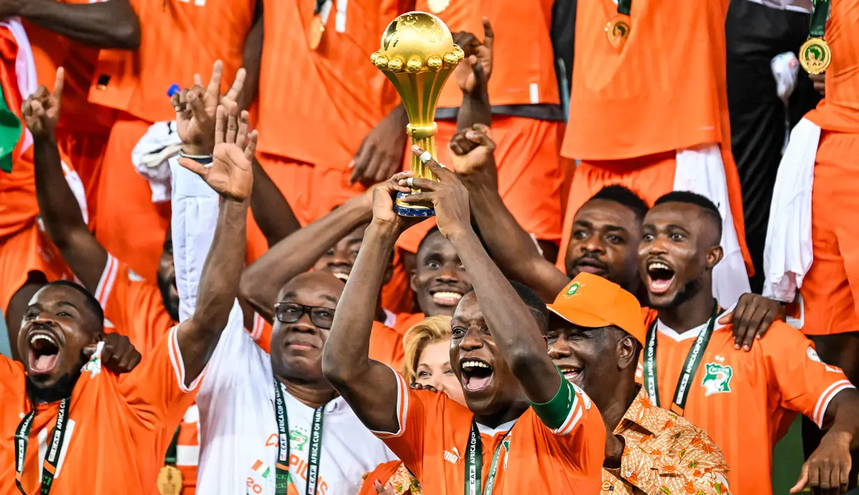 Penyerang Pantai Gading, Max-Alain Gradel (tengah) mengangkat trofi Piala Afrika di podium setelah memenangkan pertandingan sepak bola final Piala Afrika (CAN) melawan Nigeria di Stadion Olimpiade Alassane Ouattara, Ebimpe, Abidjan pada 11 Februari 2024. (Sia KAMBOU/AFP)
