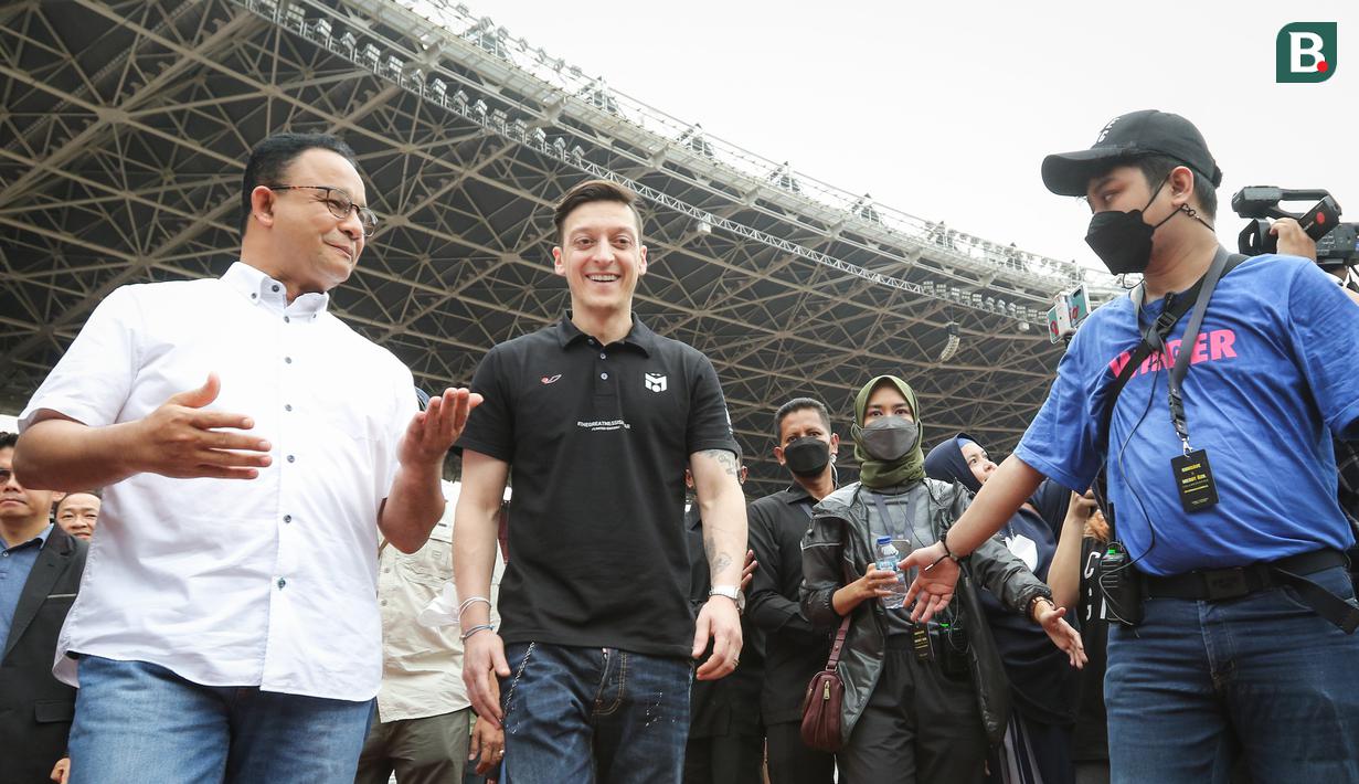 <p>Mesut Ozil (tengah) didampingi Gubernur DKI Jakarta, Anies Baswedan saat menghadiri acara coaching clinic yang digelar oleh Concave Indonesia bersama 47 anak Indonesia terpilih di Stadion Utama Gelora Bung Karno (SUGBK) Senayan, Jakarta, Kamis (26/5/2022) sore WIB. (Bola.com/Bagaskara Lazuardi)</p>