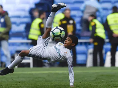 Putra dari Cristiano Ronaldo melakukan tendangan salto saat menemani sang ayah di Stadion Santiago Bernabeu, Madrid, Minggu (8/4/2018). Tendangan ini mirip seperti saat CR 7 membobol gawang Juventus. (AFP/Gabriel Bouys).