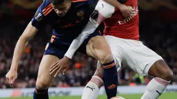 Striker Arsenal, Alexandre Lacazette berebut bola dengan pemain Valencia, Gabriel Valencia dalam leg pertama semifinal Liga Europa di Emirates Stadium, Jumat (3/5/2019). Sempat tertinggal, Arsenal berhasil mengalahkan tamunya, Valencia dengan skor 3-1. (AP/Kirsty Wigglesworth)