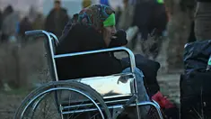 Seorang nenek dari Aleppo timur makan sambil duduk di kursi roda saat tiba di kota al-Rasyidin, Suriah (15/12). Konflik antara pemerintah dan pemberontak membuat kota Aleppo hancur. (REUTERS/Ammar Abdullah)