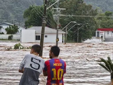 Orang-orang mengamati jalan yang banjir setelah hujan lebat di Encantado, Rio Grande do Sul, Brasil, Rabu (1/5/2024). (Photo by Gustavo Ghisleni / AFP)
