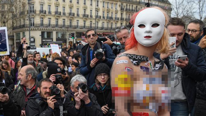 Seorang aktivis menempelkan logo merek-merek internasional pada tubuhnya saat memperingati Hari Perempuan Internasional Place de la Republique, Paris, Jumat (8/3). (Alain JOCARD/AFP)