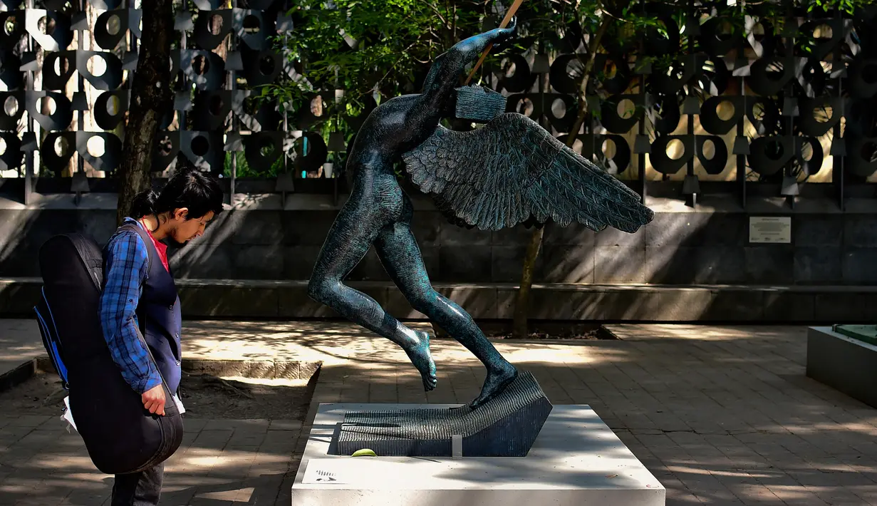 Seorang pria melihat patung " Angel of Triumph " saat pameran "Salvador Dali: Urban Dreams" di Mexico City, Selasa (14/3). Patung-patung tersebut adalah karya seniman asal spanyol yang bernama Salvador Dali. (AFP PHOTO / RONALDO SCHEMIDT)