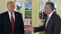 Presiden AS Donald Trump (kiri) bersama PM Singapura Lee Hsien Loong (kanan) saat akan makan siang bersama di Istana Negara Singapura, Senin (11/6). Trump akan bertemu dengan Pemimpin Korea Utara Kim Jong-un dalam acara KTT Korut-AS. (SAUL LOEB/AFP)