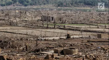 Warga melintasi bangunan di Waduk Jatigede, Desa Cipaku, Sumedang, Jawa Barat, Senin  (17/9). Musim kemarau panjang menyebabkan Waduk Jatigede surut sehingga puing bangunan Desa Cipaku yang tenggalam kembali terlihat. (Liputan6.com/Herman Zakharia)