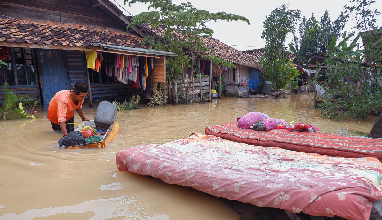 Seorang warga mengeringkan kasur dan barang-barang rumah tangga lainnya dari rumahnya yang terendam banjir di desa Sukajaya di Serang (1/3/2022).  Banjir merendam Kota Serang akibat hujan deras yang turun sejak Senin malam (28/2/2022) hingga hari ini. (AFP/Dziki Oktomauliyadi)