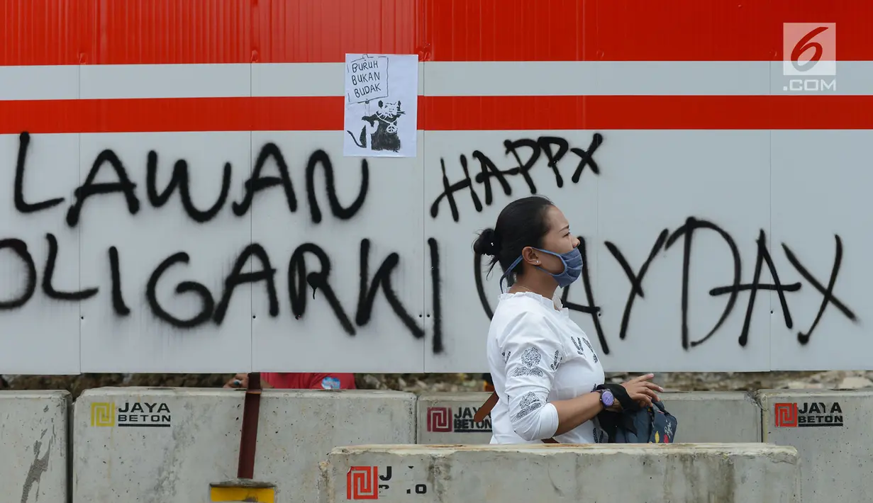 Pejalan kaki melintas dekat aksi vandalisme yang mewarnai Hari Buruh Internasional atau May Day di kawasan Bundaran HI, Jakarta, Rabu (1/5/2019). Belum diketahui siapa yang melakukan aksi corat coret di fasilitas publik tersebut. (merdeka.com/Imam Buhori)