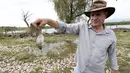 Pegiat lingkungan Antonio Huerta menunjukkan ikan yang mati di tepi Sungai Santiago, salah satu sungai yang paling tercemar di Meksiko, di Juanacatlan, Negara Bagian Jalisco, Meksiko pada 17 Juli 2024. (ULISES RUIZ / AFP)