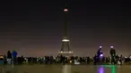 Pengunjung berkumpul di alun-alun Trocadero saat lampu Menara Eiffel di Paris, dipadamkan, Rabu (24/5) dini hari. Hal itu sebagai bentuk penghormatan dan duka cita atas serangan bom pada konser Ariana Grande di Manchester, Inggris (AP Photo/Francois Mori)