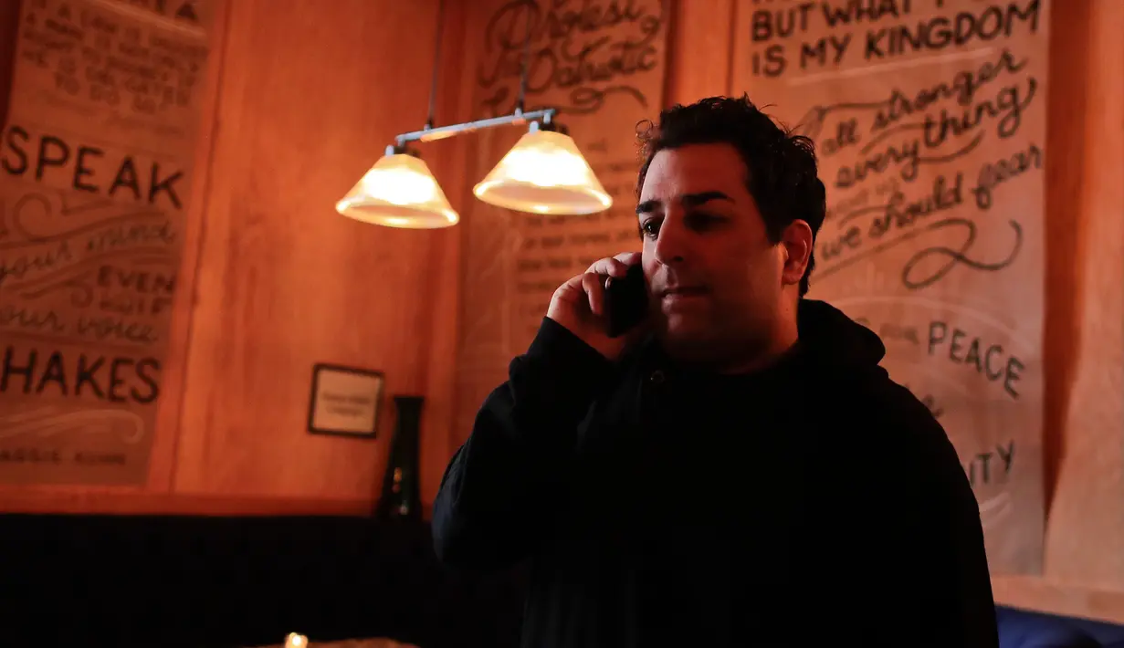 Pendiri bar Ravi DeRossi berbicara di telepon sebelum pembukaan bar anti-Trump di New York City (25/4). Bar yang baru dibuka ini merupakan bentuk tanggapan terhadap pemerintah Donald Trump. (AP Photo/Julie Jacobson)