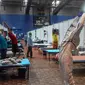 Seorang dokter yang mengenakan setelan Alat Pelindung Diri memberikan instruksi kepada pasien saat melakukan yoga di dalam bangsal di kompleks olahraga Commonwealth Games (CWG) Village yang sementara diubah menjadi pusat perawatan Covid-19 di New Delhi, India, Kamis (16/7/2020). (Money SHARMA / AFP)