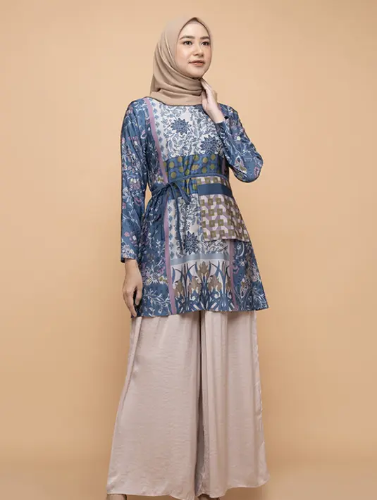 <p>Iskanti Daarya tunik didominasi warna biru bermotif ini bisa dipadukan dengan pallazo pants warna pink yang serasi dengan warna kerudungnya. Credit: Blibli</p>