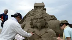 Seniman patung pasir berusaha menyelesaikan karya mereka yang diberi nama "Nihon Shoki" atau "The Chronicles of Japan" yang akan dipamerkan dalam Asahi Sand Sculpture di pantai Yasashigaura, Asahi, Chiba, (13/7/2014). (AFP PHOTO/Toshifumi Kitamura)