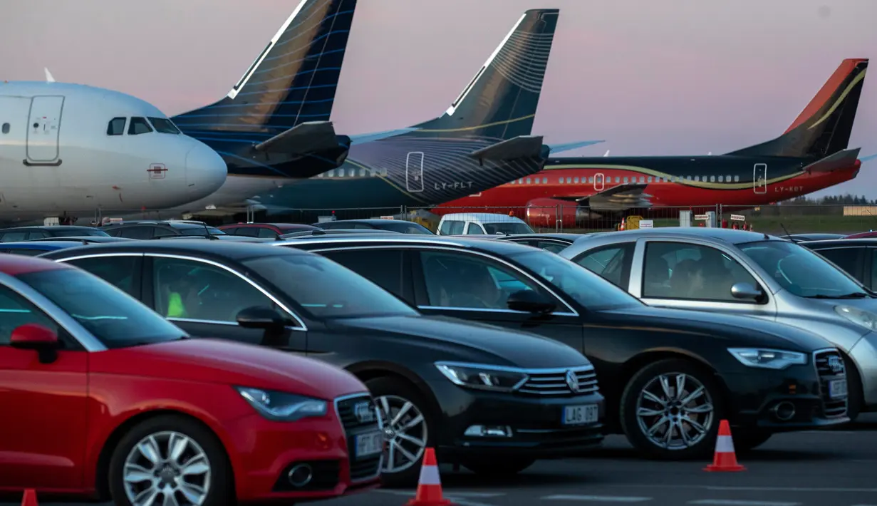 Sejumlah penonton duduk di mobil mereka saat menonton film di bioskop drive-in di area apron bandara , tempat pesawat lepas landas dan mendarat ketika bioskop biasa ditutup karena wabah virus Corona di Vilnius, Lithuania pada 29 April 2020. (AP/Mindaugas Kulbis)