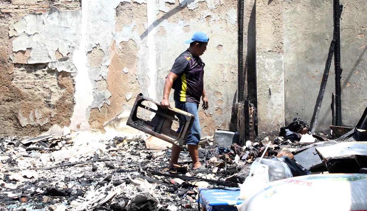 Pemilik kios membersihkan puing-puing bangunan usai kebakaran yang melanda deretan kios di kawasan Kalibata, Jakarta Selatan, pada Jumat (12/12/2025). Kebakaran hebat terjadi setelah kericuhan pada Kamis (11/12/2025) malam. (merdeka.com/magang/Rendi Saputra)