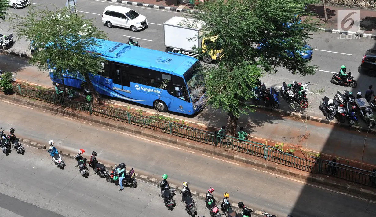 Bus Transjakarta melintasi sepeda motor pengendara ojek online yang terparkir di badan jalan kawasan Mangga Dua, Jakarta, Selasa (23/4). Kurangnya pengawasan dan tidak disiplinnya pengendara ojek online menyebabkan kemacetan kendaraan yang melintas di kawasan tersebut. (merdeka.com/Iqbal S. Nugroho)