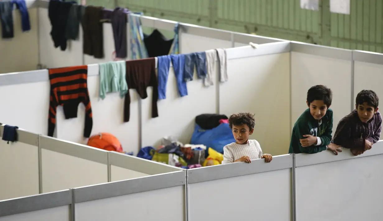 Sejumlah anak berdiri di ruang tidur bagi para migran yang didirikan di dalam hanggar bekas bandara Tempelhof di Berlin, Jerman, Rabu (9/12/2015). Jerman menerima satu juta migran dari beberapa negara yang sedang dilanda perang. (REUTERS/Fabrizio Bensch)