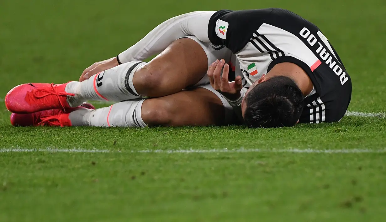 Pemain Juventus Cristiano Ronaldo terbaring di lapangan setelah ditackle pemain AS Roma Chris Smalling pada pertandingan Coppa Italia di Turin, Italia, Rabu (22/1/2020). Juventus menggilas AS Roma 3-1 dan berhasil lolos ke semifinal. (Marco Bertorello/AFP)