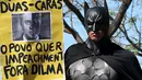 Aktivis mengenakan kostum Batman membawa tulisan berisi protes kepada Presiden Brasil Dilma Rousseff di Gedung Kongres Nasional, Brasil (27/5/2015). Tuntutan ini didasari banyaknya kasus korupsi yang menjerat Presiden Dilma. (REUTERS/Adriano Machado)