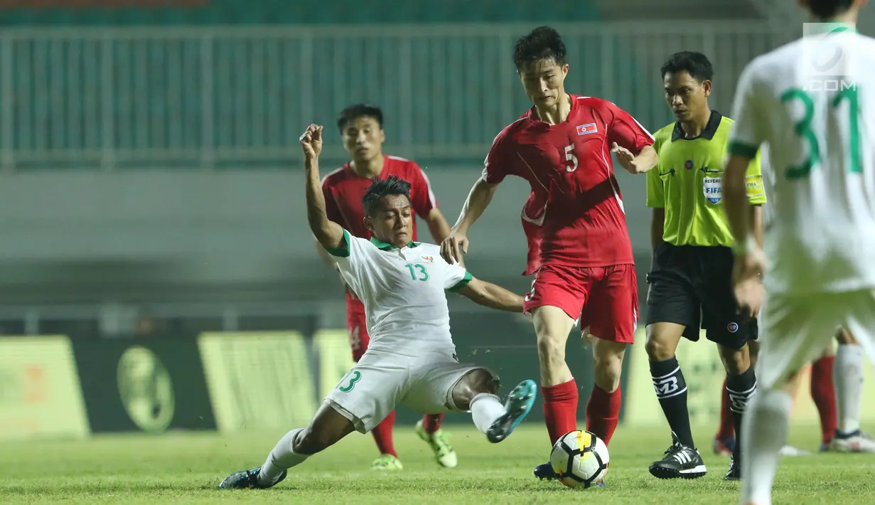 Pemain sayap Indonesia U-23, Febri Hariyadi (kiri) mencoba menahan pemain Korea Utara, Jon Se Gye pada laga PSSI Anniversary Cup 2018 di Stadion Pakansari, Kab Bogor, Senin (30/4). Laga berakhir imbang 0-0. (Liputan6.com/Helmi Fithriansyah)