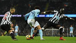 Gelandang Manchester City, Leroy Sane berebut bola dengan pemain Newcastle United, DeAndre Yedlin dan Mohamed Diame pada pertandingan pekan ke-24 Premier League di Etihad Stadium, Minggu (21/1). Manchester City meraih kemenangan 3-1. (Oli SCARFF/AFP)