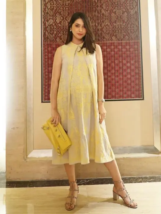 Nabila memilih midi dress bernuansa kuning dengan model belahan di tengah. Clutch kuning melengkapi tampilan soft nan elegan. (Instagram/nysyakieb65).