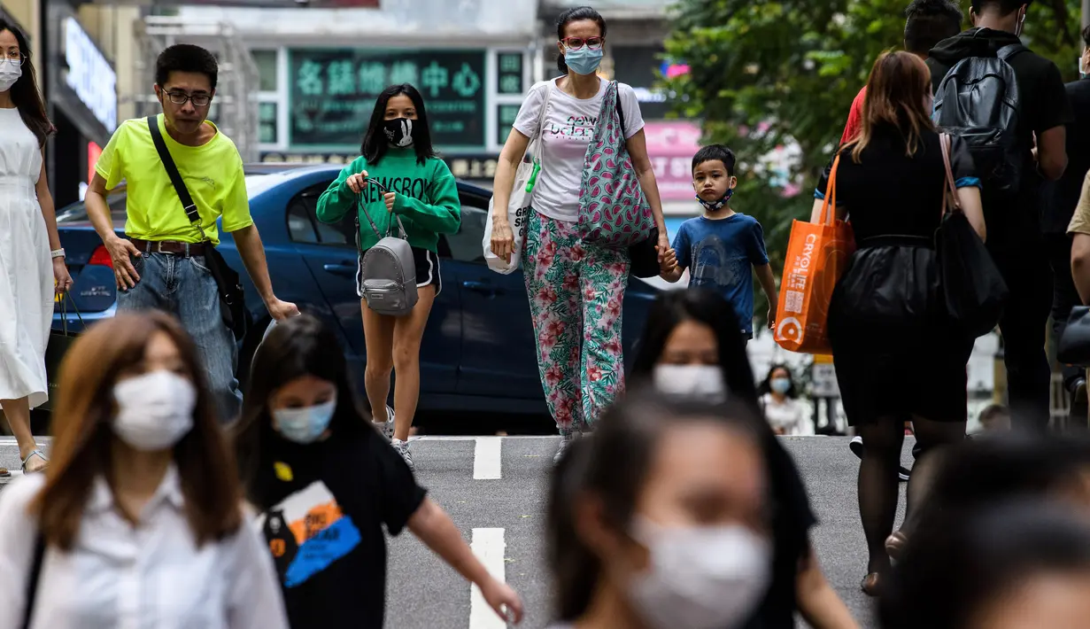 Pejalan kaki mengenakan masker sebagai tindakan pencegahan Covid-19 saat berjalan di Hong Kong (13/5/2020). Dua orang di Hong Kong dinyatakan positif Covid-19, mengakhiri perjalanan 24 hari tanpa kasus baru yang mulai melonggarkan peraturan jarak sosial. (AFP/Anthony Wallace)