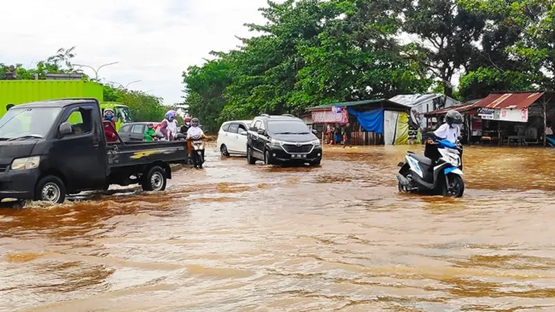 Warga mendorong sepeda motor karena mogok akibat nekat melintasi banjir di Pekanbaru.