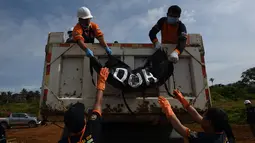 Petugas menurunkan jenazah korban pengepungan Marawi saat pemakaman massal di sebuah pemakaman umum di Marawi, di pulau selatan Mindanao (24/7). Perang di Marawi memasuki bulan kedua. (AFP Photo/Ted Aljibe)