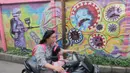Warga melintasi mural bertema covid-19 di Tanah Tinggi, Tangerang, Sabtu (29/1/2022). Kasus Covid-19 varian Omicron di Indonesia terus bertambah dan wilayah penyebarannya semakin meluas. Diperkirakan, kasus omicron sudah mendominasi penularan virus corona di Jawa Bali. (Liputan6.com/Angga Yuniar)
