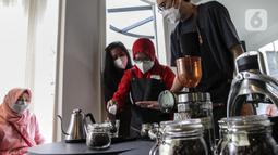 Praktisi (kanan) mengajar pembuatan kopi kepada anak berkebutuhan khusus di The Home, Cilandak, Jakarta, Selasa (11/1/2022). Belajar membuat kopi merupakan salah satu pelatihan khusus yang disesuaikan dari minat anak berkebutuhan khusus setelah selesai pendidikan di SLB. (Liputan6.com/Johan Tallo)