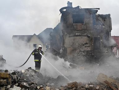 Petugas pemadam kebakaran memadamkan api di rumah-rumah pribadi yang rusak setelah serangan Rusia di wilayah Kyiv pada 25 Mei 2025, di tengah invasi Rusia di Ukraina. (Sergei SUPINSKY/AFP)