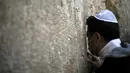 Seorang pria mengenakan masker berdoa di Tembok Ratapan di Kota Tua Yerusalem (16/2/2020). Ketika kekhawatiran tentang penyebaran virus corona meningkat, umat Yahudi yang setia mengadakan sesi doa untuk mencari intervensi ilahi untuk membantu mencegah penyakit tersebut. (AP Photo/Ariel Schalit)