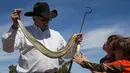 Cliff Jones menunjukkan ular derik di depan JD Farmer (9) dan Carter Farmer (7) setelah melakukan perburuan dalam kompetisi Roundup Rattlesnake Sweetwater di Texas, Amerika Serikat, Sabtu (10/3). (Loren Elliott/AFP)