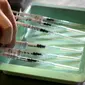 Seorang tentara Swiss menyiapkan jarum suntik dengan vaksin COVID-19 Biontech/Pfizer di Delemont, Swiss, 14 Desember 2021. Swiss yang dilanda gelombang infeksi baru COVID-19 telah memanggil tentara untuk mempercepat vaksinasi.
(Fabrice COFFRINI/AFP)