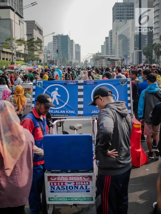 Warga membeli minuman ke pedagang kaki lima (PKL) yang berjualan di kawasan car free day (CFD), Bundaran HI, Jakarta, Minggu (4/8/2019). Kurangnya pengawasan petugas menyebabkan banyak PKL berjualan tidak pada tempat yang telah disediakan oleh Pemprov DKI Jakarta. (Liputan6.com/Faizal Fanani)