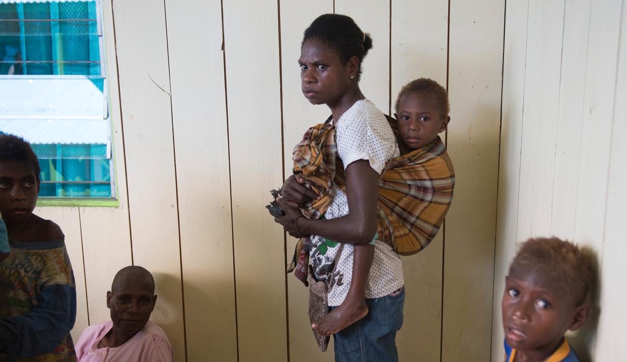 Seorang wanita menggendong anaknya untuk menunggu perawatan medis di klinik setempat di desa Ayam distrik Asmat, di provinsi Papua Barat (26/1). (AFP/Bay Ismoyo)