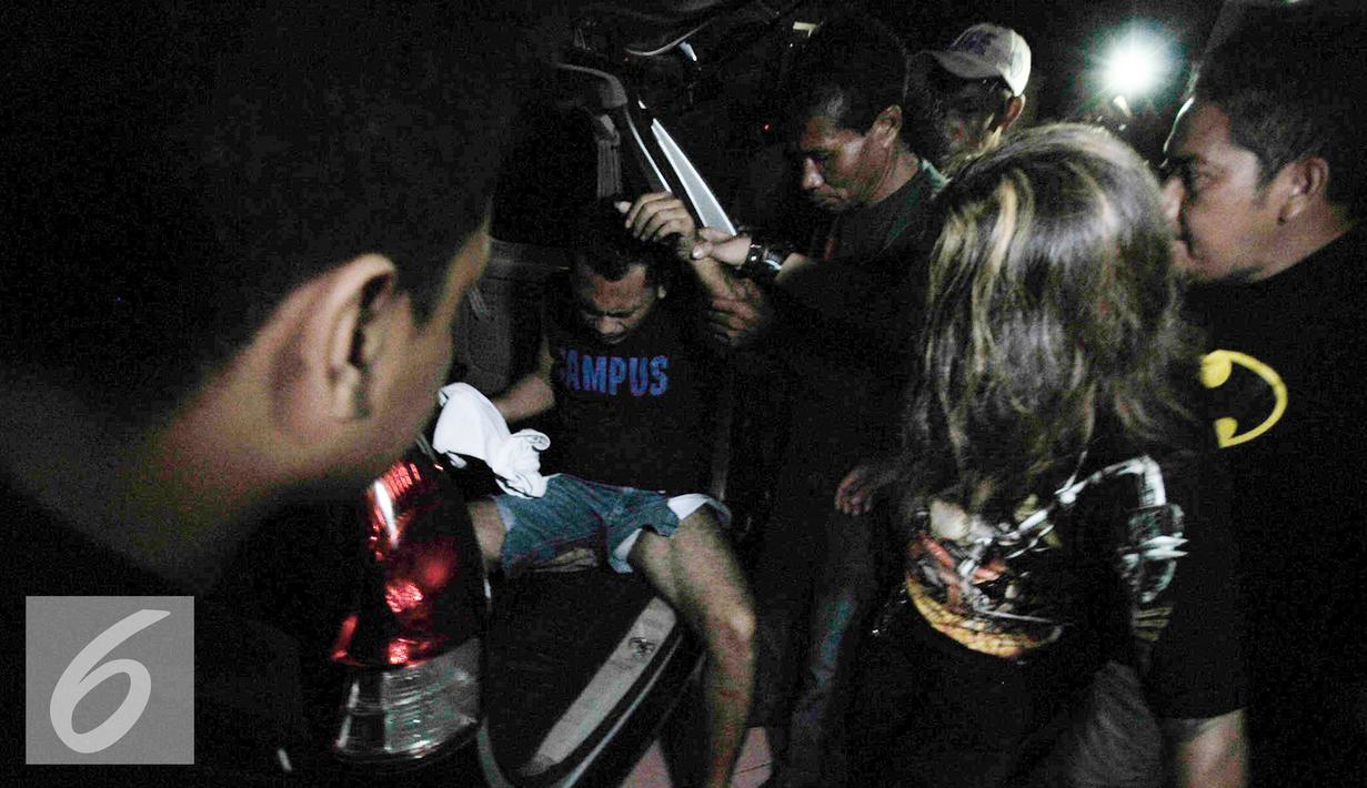 Petugas menurunkan Alfin Bernius Sinaga, supir perampokan disertai pembunuhan di Pulomas saat tiba di RS Polri, Kramatjati, Jakarta Timur, Kamis (29/12). (Liputan6.com/Yoppy Renato) 