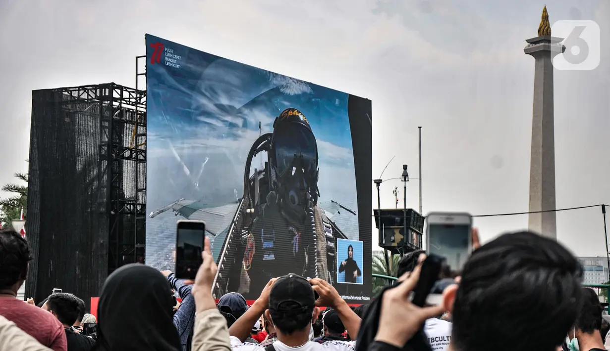 Warga menyaksikan manuver pesawat tempur TNI AU saat perayaan HUT ke-77 Republik Indonesia (RI) di Taman Aspirasi Monumen Nasional (Monas), Jakarta Pusat, Rabu (17/8/2022). Aksi akrobatik pesawat tempur dan helikopter yang membawa bendera Merah Putih tersebut disambut antusias oleh warga yang datang untuk mengikuti upacara Kemerdekaan RI. (merdeka.com/Iqbal S Nugroho)