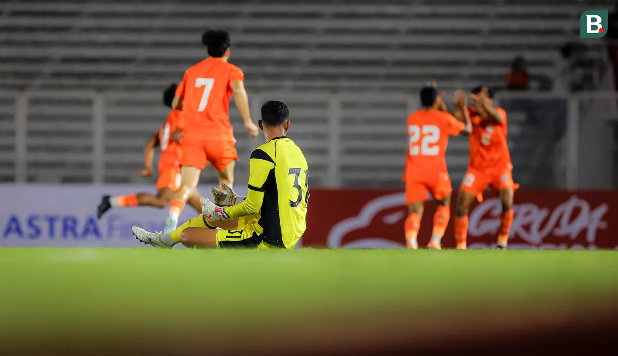 Kiper Timnas Indonesia U-22, Erlangga Setyo melihat selebrasi pemain India setelah mencetak gol ke gawangnya dalam laga uji coba di Stadion Madya, Senayan, Jakarta, Minggu (13/10/2025). (Bola.com/Bagaskara Lazuardi)
