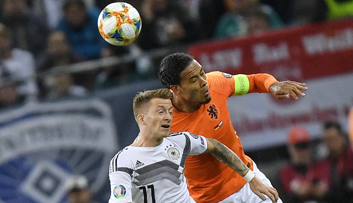 Bek Belanda, Virgil Van Dijk berebut bola udara dengan gelandang Jerman, Marco Reus selama pertandingan grup C  kualifikasi Euro 2020 di Hamburg, Jerman (6/9/2019). Belanda menang telak 4-2 atas Jerman. (AP Photo/Martin Meissner)