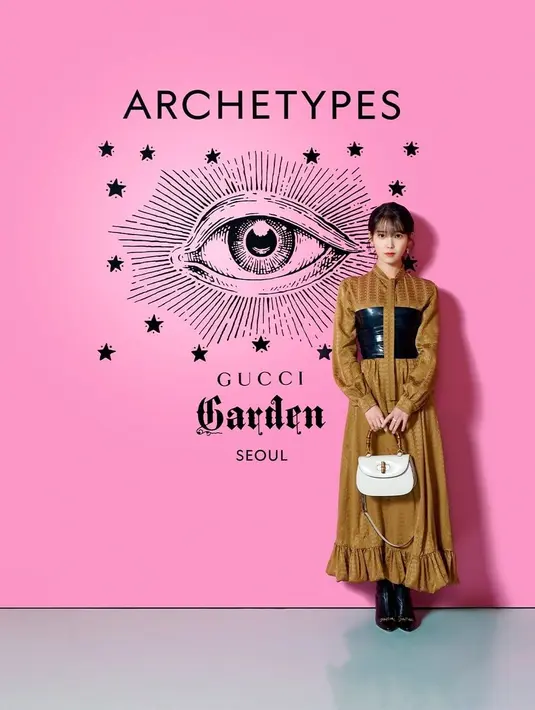 IU tampil di red carpet mengenakan Gucci Love Parade dari look 111, dengan crepe satin GG stripe long sleeve dress berwarna sand brown dengan self-fabric bow, atasan lateks hitam, dan sepatu boot kulit hitam berdetail rantai. Foto: Document/Gucci.