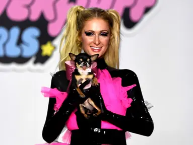 Paris Hilton membawa anjing saat tampil dalam Christian Cowan x The Powerpuff Girls Fashion Show, Los Angeles, AS, Jumat (8/3). Anjing tersebut merupakan peliharaannya yang bernama Diamond Baby. (Frazer Harrison/Getty Images North America/AFP)