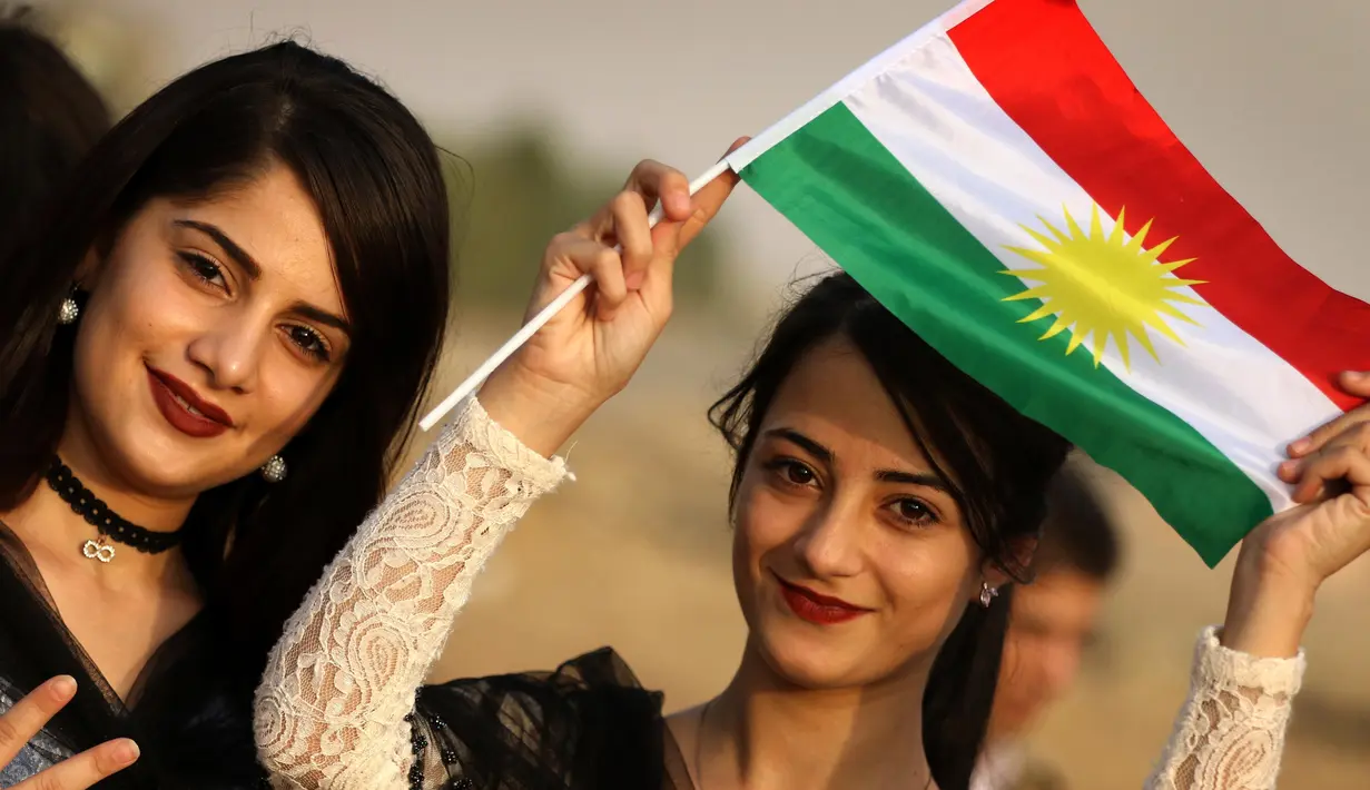 Seorang gadis Kurdi Iran memegang bendera Kurdi saat mengampanyekan referendum untuk kemerdekaan di kota Bahirka, Irak Utara (21/9). Mereka meminta referendum untuk menentukan kemerdekaan etnis Kurdi di Irak. (AFP Photo/Safin Hamed)