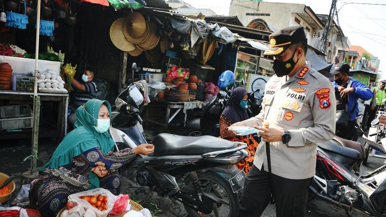 Kapolrestabes Surabaya Kombes Pol Akhmad Yusep Gunawan membagikan masker ke pedagang pasar di Surabaya. (Dian Kurniawan/Liputan6.com)