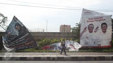 Pejalan kaki melewati alat peraga kampanye Pilkada DKI 2017 yang rusak di kawasan Ancol, Jakarta, Selasa (3/1). Kurangnya pengawasan menyebabkan alat peraga kampanye di sejumlah sudut Ibu Kota mengalami kerusakan. (Liputan6.com/Immanuel Antonius)